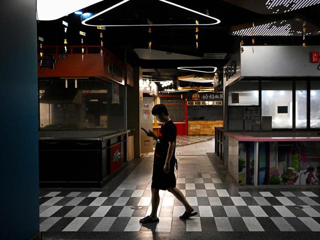 A man walks past closed food stalls at a mall in Beijing on August 15, 2023. Global stocks fell on August 15, after disappointing data from China deepened concerns over the state of the world's second-largest economy. (Photo by Greg Baker / AFP)