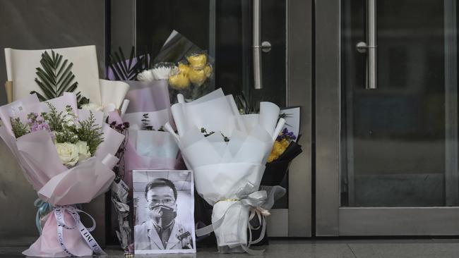 A portrait of Dr Li Wenliang was left with flowers at his hospital in Wuhan on Friday. Picture: Getty Images