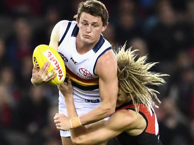 Matt Crouch of the Crows handballs whilst being tackled by Dyson Heppell of the Bombers.