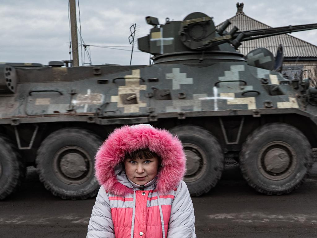 Lisa Shtanko, 8-year-old, looks on as a military vehicle passes behind in front of her house in the city of Lyman, eastern Ukraine. Picture: AFP