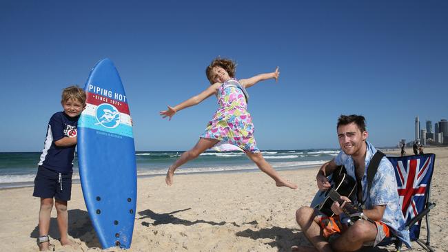 Flashback to 2016 — Connor Bentley-Gibbons, 7, and Petra Dennett, 8, enjoy their time out on the beach during school holidays while musician Edward Sarroff plays the guitar at Main Beach, Gold Coast. Photo: Regi Varghese.