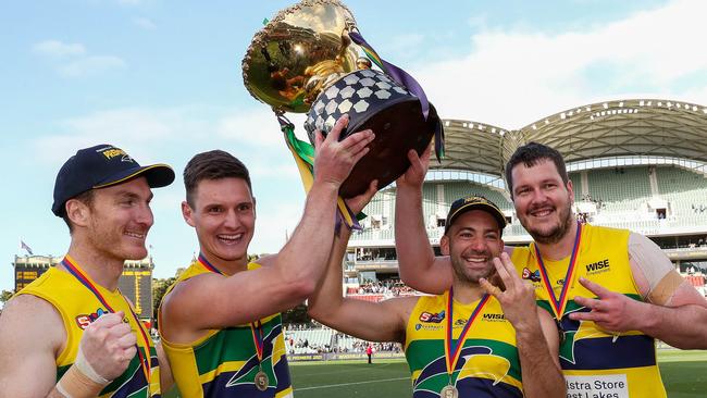 Luke Thompson (second from left) holds the 2021 SANFL premiership cup aloft with fellow triple Eagles premiership players, from left, Patrick Giuffreda, Jimmy Toumpas and Jarrad Redden. Picture: Sarah Reed