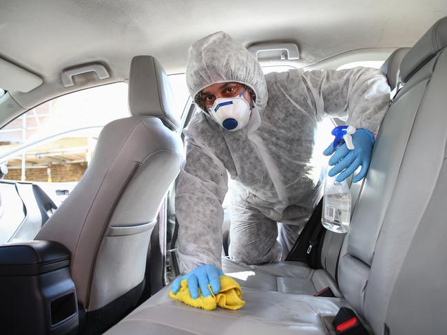 London Uber driver Yasar Gorur wears personal protective equipment while cleaning his vehicle. Picture: Getty Images