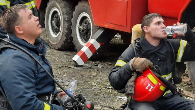 This handout picture released by the State Emergency Service of Ukraine on June 13, 2023, shows firefighters taking a rest as they extinguish a fire on a five-storey residential building, the site of a night Russian strike, in the city of Kryvyi Rig, amid the Russian invasion of Ukraine. Three people were killed and 32 wounded in a Russian missile strike on the central Ukrainian city of Kryvyi Rih early June 13, 2023, the regional governor said, as air attacks were reported in Kyiv and other cities. 
