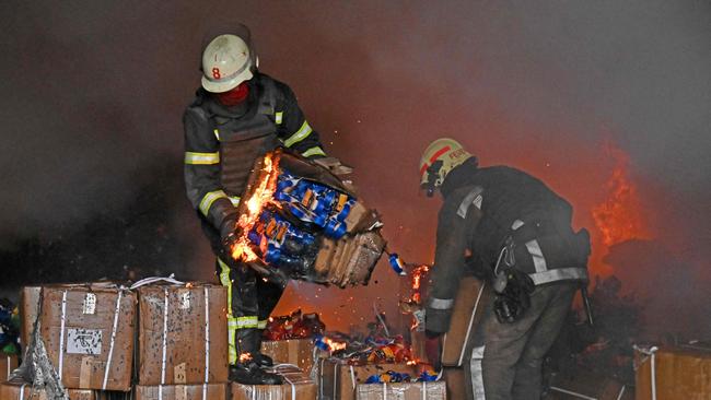 Firefighters hold boxes as they try to extinguish a fire after a missile hit a warehouse on the outskirts of Kharkiv on April 13.