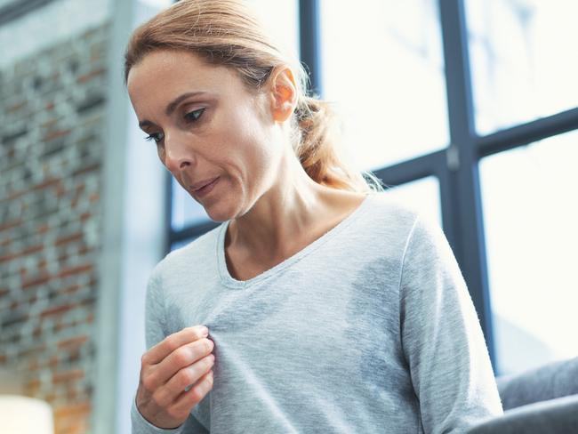 Gradual process. Beautiful mature woman touching sweater and having hot flash