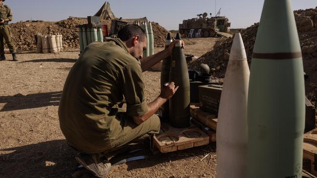 A soldier from an Israeli artillery unit writes on a missile as he waits for orders to fire from the Israeli side of the border towards the Gaza Strip. Picture: Getty