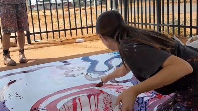 Rosie Palmer, manager of the Tjala Arts centre in the APY Lands of South Australia, is seen appearing to paint on the work of Indigenous artist Yaritji Young.