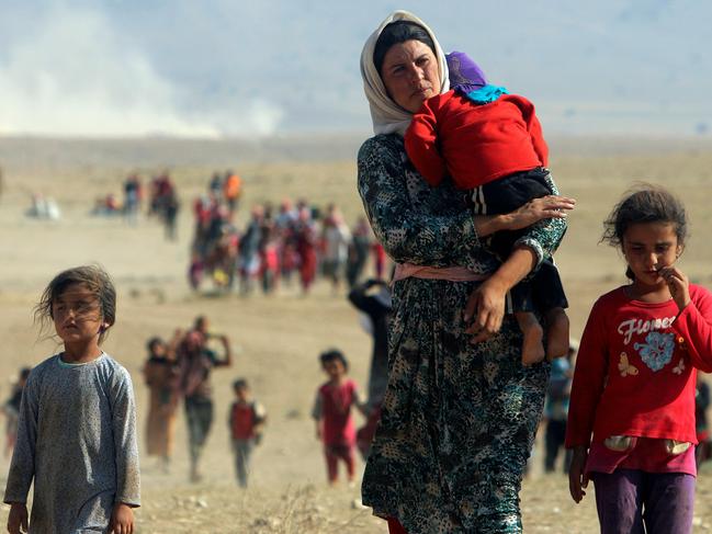 Displaced people from the minority Yazidi sect, fleeing violence from forces loyal to the Islamic State in Sinjar town, walk towards the Syrian border on the outskirts of Sinjar mountain near the Syrian border town of Elierbeh of Al-Hasakah Governorate in this August 11, 2014. REUTERS/Rodi Said/File Photo - RTX2GIWQ