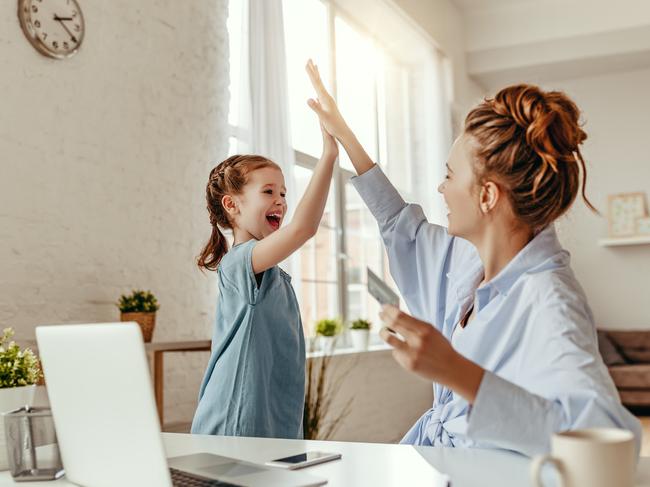 Low angle of excited small daughter giving high five to mother and screaming while celebrating successful online shopping using laptop at table in light living room Picture: Istock