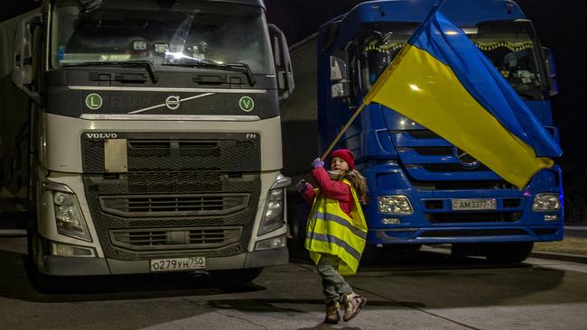 Camilla waves the Ukrainian flag at the urging of her father at the Polish-Belarus border on Sunday. Picture: Annabel Moeller