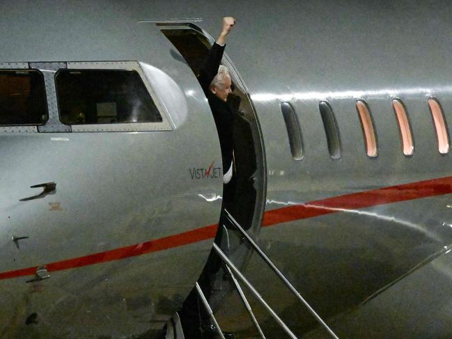 Julian Assange raises his fist from the door of the plane after arriving at Canberra Airport. Picture: AFP