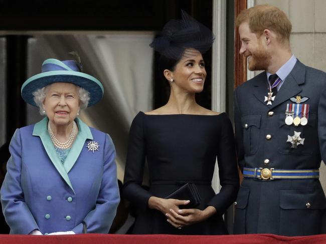 FILE - In this Tuesday, July 10, 2018 file photo Britain's Queen Elizabeth II, and Meghan the Duchess of Sussex and Prince Harry watch a flypast of Royal Air Force aircraft pass over Buckingham Palace in London. As part of a surprise announcement distancing themselves from the British royal family, Prince Harry and his wife Meghan declared they will â€œwork to become financially independentâ€ _ a move that has not been clearly spelled out and could be fraught with obstacles. (AP Photo/Matt Dunham, File)