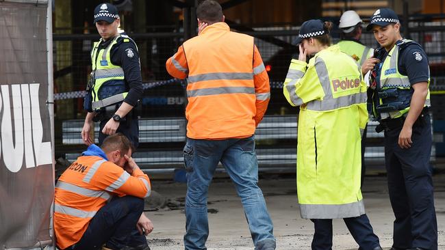 A construction worker is overcome with grief at the site of an accident in South Wharf, where a worker was killed. Picture: Jake Nowakowski