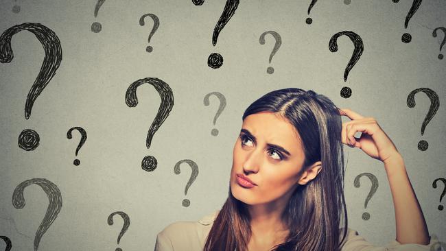 Portrait confused thinking young woman bewildered scratching her head seeks a solution looking up at many question marks isolated on gray wall background. Human face expression