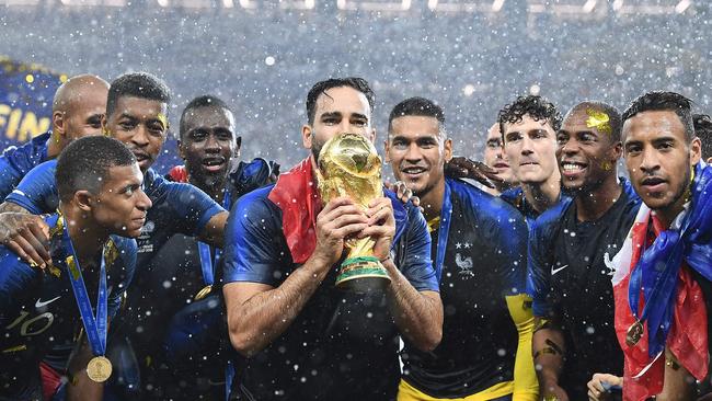 France's defender Adil Rami (C) kisses their World Cup trophy as he celebrates with teammates during the trophy ceremony at the end of the Russia 2018 World Cup final football match between France and Croatia at the Luzhniki Stadium in Moscow on July 15, 2018. / AFP PHOTO / FRANCK FIFE / RESTRICTED TO EDITORIAL USE - NO MOBILE PUSH ALERTS/DOWNLOADS