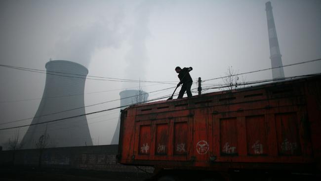 A truck driver shovels coal hear a coal-fired power plant in Linfen, China.