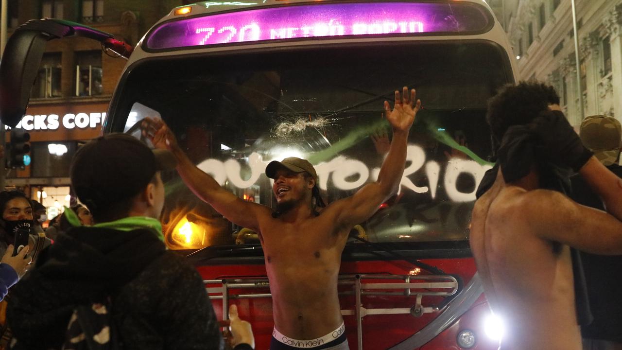 Rioters next to a vandalised bus. Picture: Jae C. Hong/AP