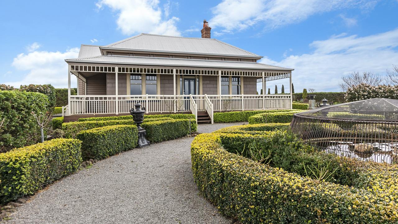 The house is flanked by greenery.