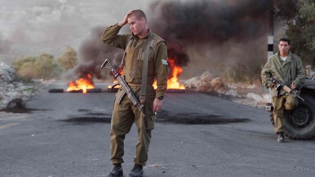 Israeli soldiers stand near a roadblock of burning tires placed by Jewish settlers. Picture: Sven Nackstrand/AFP)