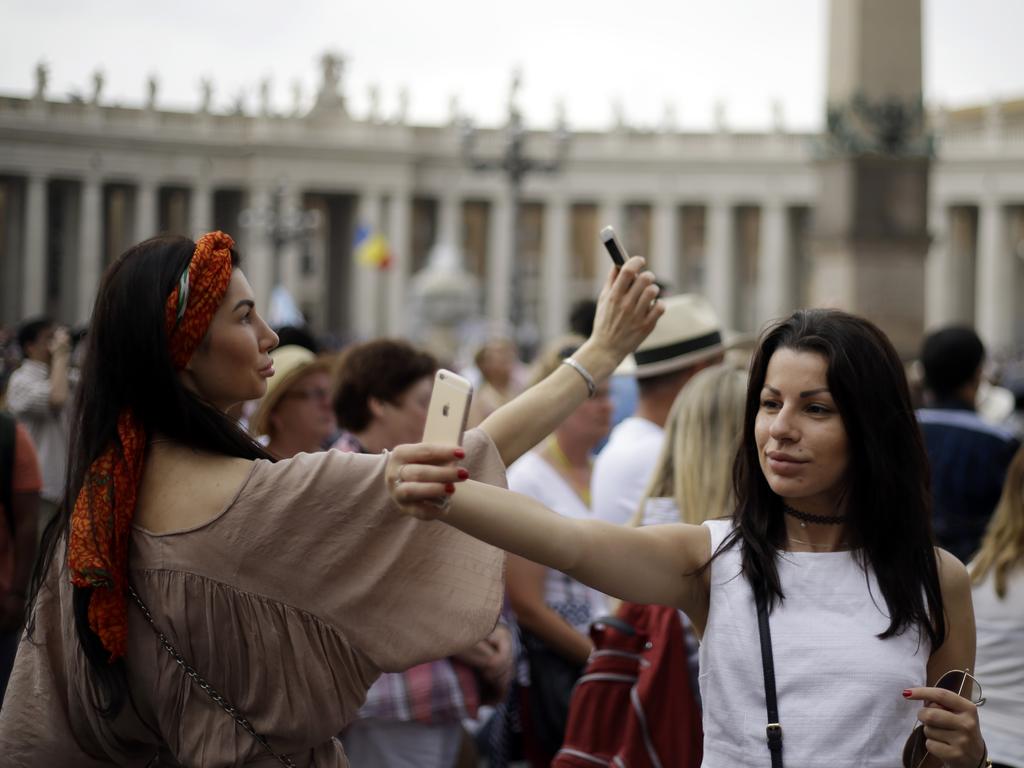 Tourists take selfies next to the Bernini colonnade, in St. Peter's Square at the Vatican, Sunday, June 14, 2015. (AP Photo/Gregorio Borgia)