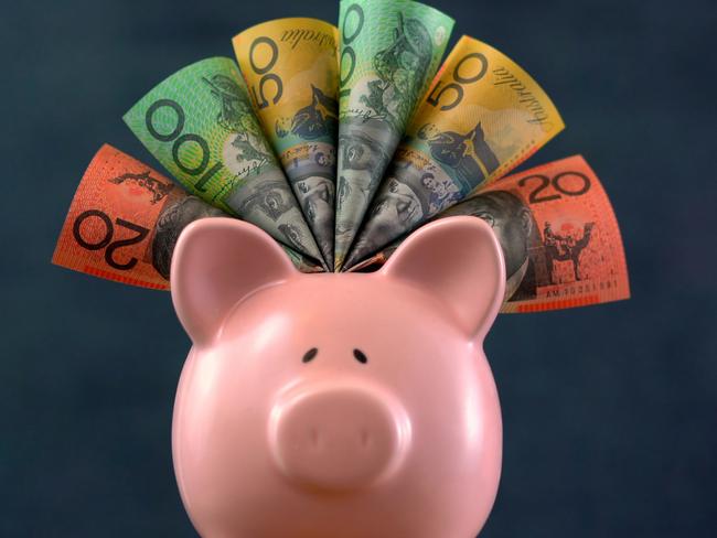 Pink Piggy bank money concept on dark blue background, stuffed with Australian cash.