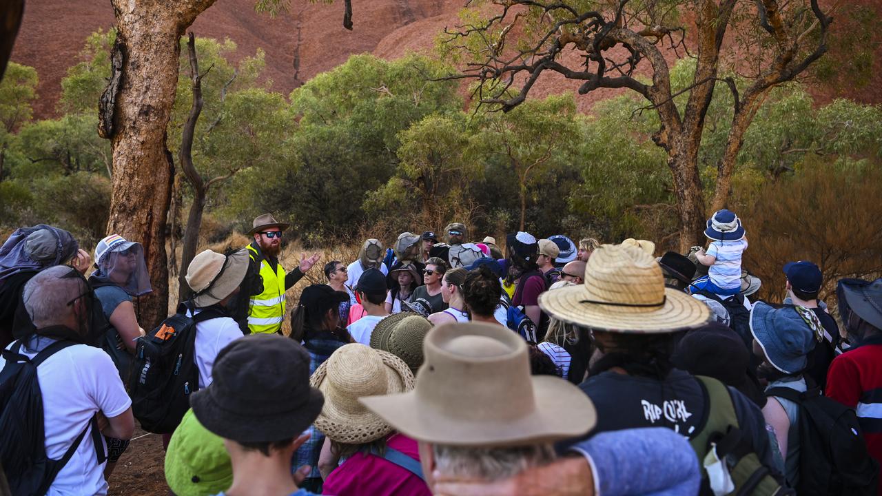 A tour guide speaks to tourists at the bottom of Uluru. Picture: Lukas Coch/AAP