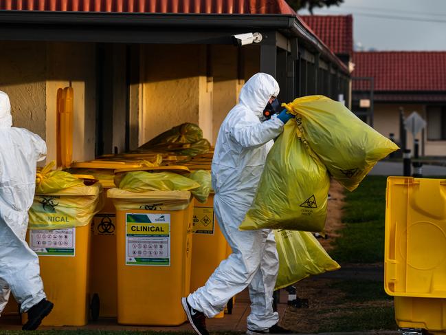 Workers in full protective gear dispose of waste. Picture: Jason Edwards