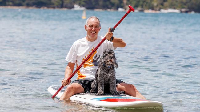 Parkinson's disease sufferer Clyde Campbell AM, the founder of the Shake it Up Foundation, and his dog and paddle board companion Zeb at Balmoral Beach in Sydney.