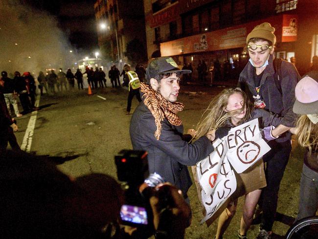 A woman flees chemical irritants detonated by police in Oakland, California. Picture: AP