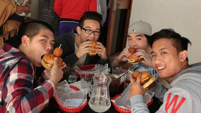 Customers chow down on their free burgers. Picture: Robert Pozo