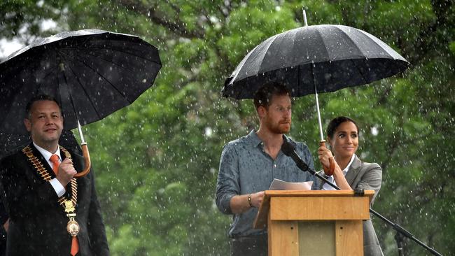 Dubbo mayor Ben Shields look on as Prince Harry speaks to the community as his wife Meghan, Duchess of Sussex keeps him dry in October 2018. Picture: Peter Parks/AFP