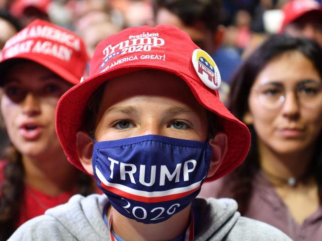 A young supporter wears a Trump 2020 mask as he listens to US President Donald Trump speak during a campaign rally at the BOK Center in Tulsa, Oklahoma.