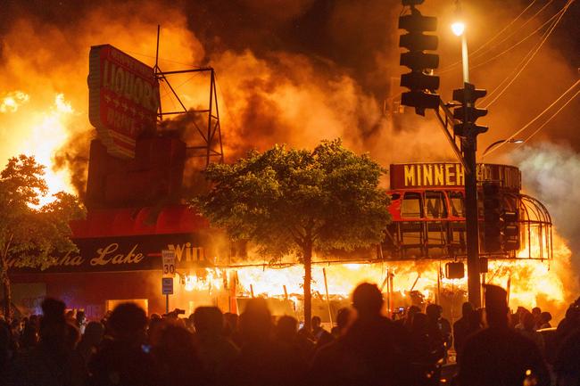 Protesters gather in front of a liquor store in flames near the Third Police Precinct in Minneapolis. Picture: AFP