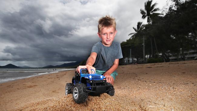 The weather in Cairns will remain cloudy with showers and steady rain this week. Koby Henderson, 7, of Palm Cove, plays with his toy truck on the beach as dark clouds gather behind him. Picture: Brendan Radke