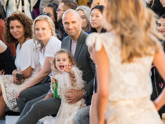 Chris Judd and daughter Billie watch Rebecca Judd on a VAMFF runway.