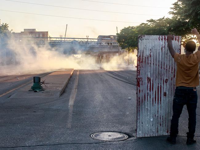 A protester stands behind a piece of metal as tear gas is fired in Minneapolis, Minnesota. Picture: AFP