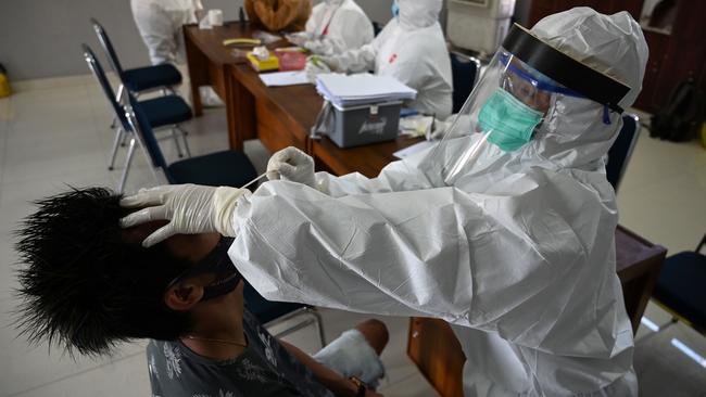 A medical staff member takes a swab sample from a man for a COVID-19 test in Denpasar, Bali. Picture: AFP