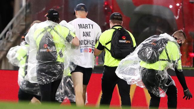 A pitch invader is escorted away by security. Picture: Sarah Reed