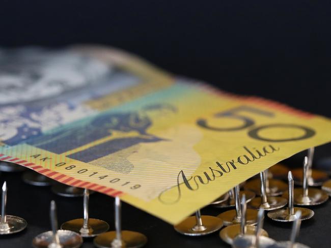 close up extreme shallow depth of field macro shot of australian fifty dollar note supported on sharp thumb tacks or drawing pins. Finance business economy concept. Debt trap generic money