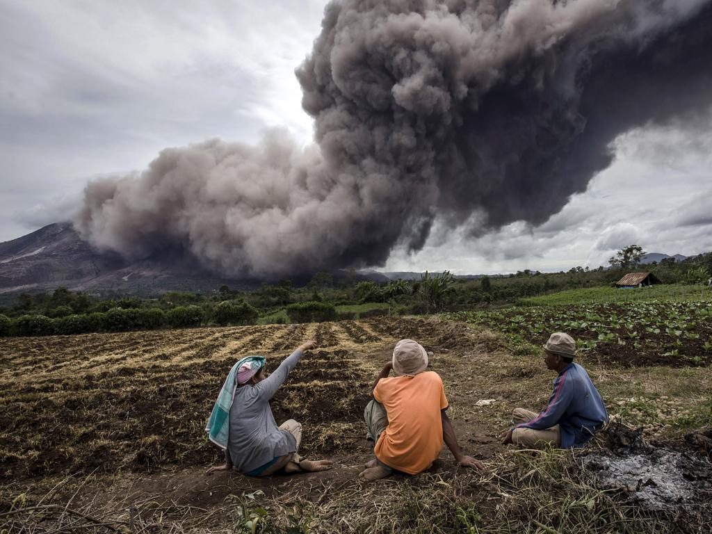 Local farmers pause from their work as Mount Sinabung spews pyroclastic smoke, seen from Tiga Kicat village on June 17, 2015 in Sukanalu village, North Sumatra, Indonesia. Picture: Getty