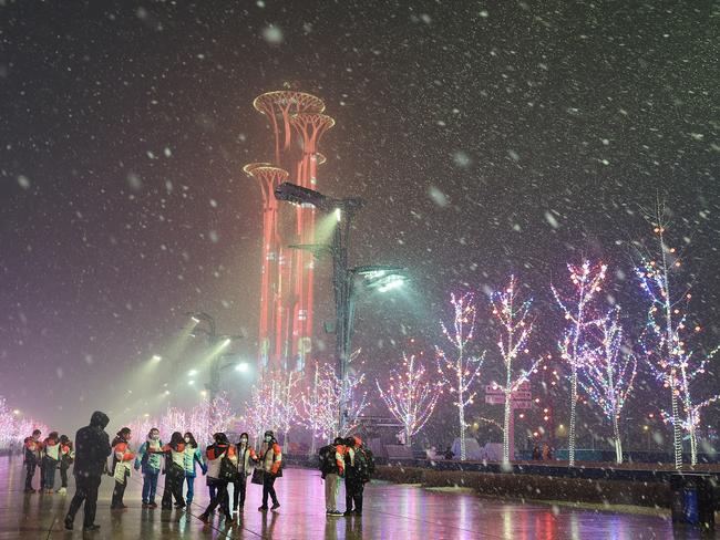 Volunteers pose for a picture in the snow near the Olympic Tower ahead of the Beijing Winter Olympics in Beijing, China. Picture: Getty Images