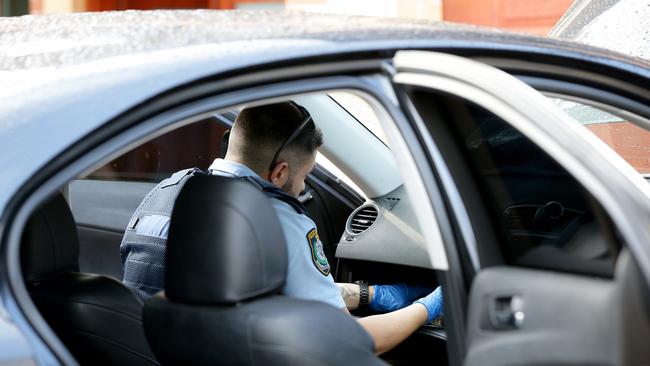 Police search through vehicles at a property in Auburn. Picture: Jonathan Ng