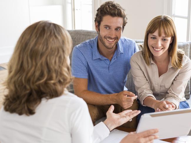 A young couple reviewing their home loan with a mortgage broker. Picture: iStock.