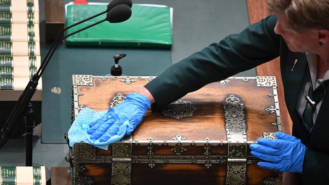 A parliamentary attendant disinfects the dispatch box before Question Time. Picture: AAP