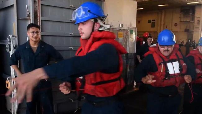 Sailors on the USS America help tighten a cable that was shot over to the HMAS Ballarat to prepare for a replenishment at sea, or to refuel the Ballarat during Exercise Talisman Sabre 2021 in this still from a video. Picture: Supplied