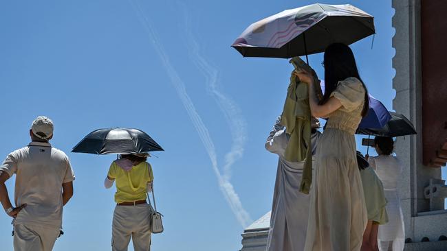 Smoke trails from missiles launched by the Chinese military are seen as tourists look on from Pingtan island, one of mainland China's closest points to Taiwan, in Fujian province, (Photo by Hector RETAMAL / AFP)