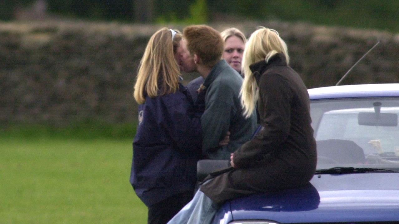 Sasha (rears) looks on as Prince Harry greets another friend with a kiss at the polo. (Photo by Antony Jones/UK Press via Getty Images)