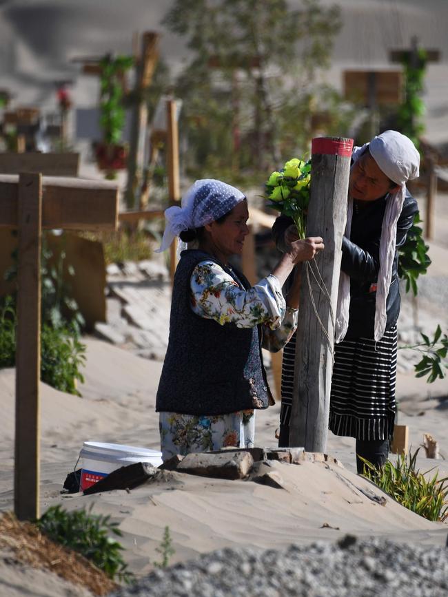 Two women decorate a grave in a Uighur cemetery in Xinjiang in May. Picture: AFP