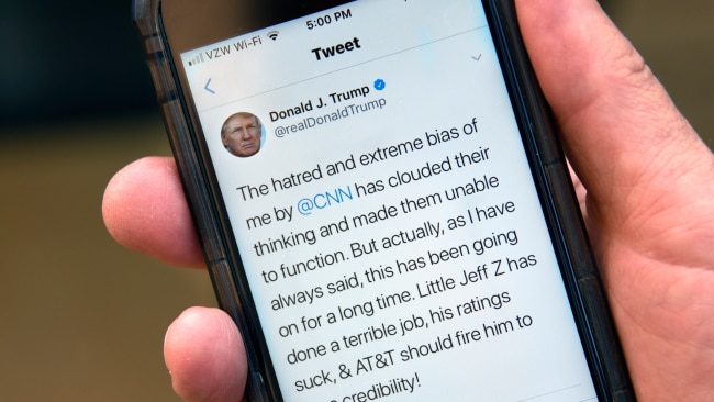 A man uses his smartphone to read a tweet from U.S. President Donald Trump attacking CNN and the television network's president, Jeff Zucker, for alleged media bias.  (Photo by Robert Alexander/Getty Images)